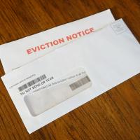 Image of a letter with the words "Eviction Notice" inside an envelope on a wood table.
