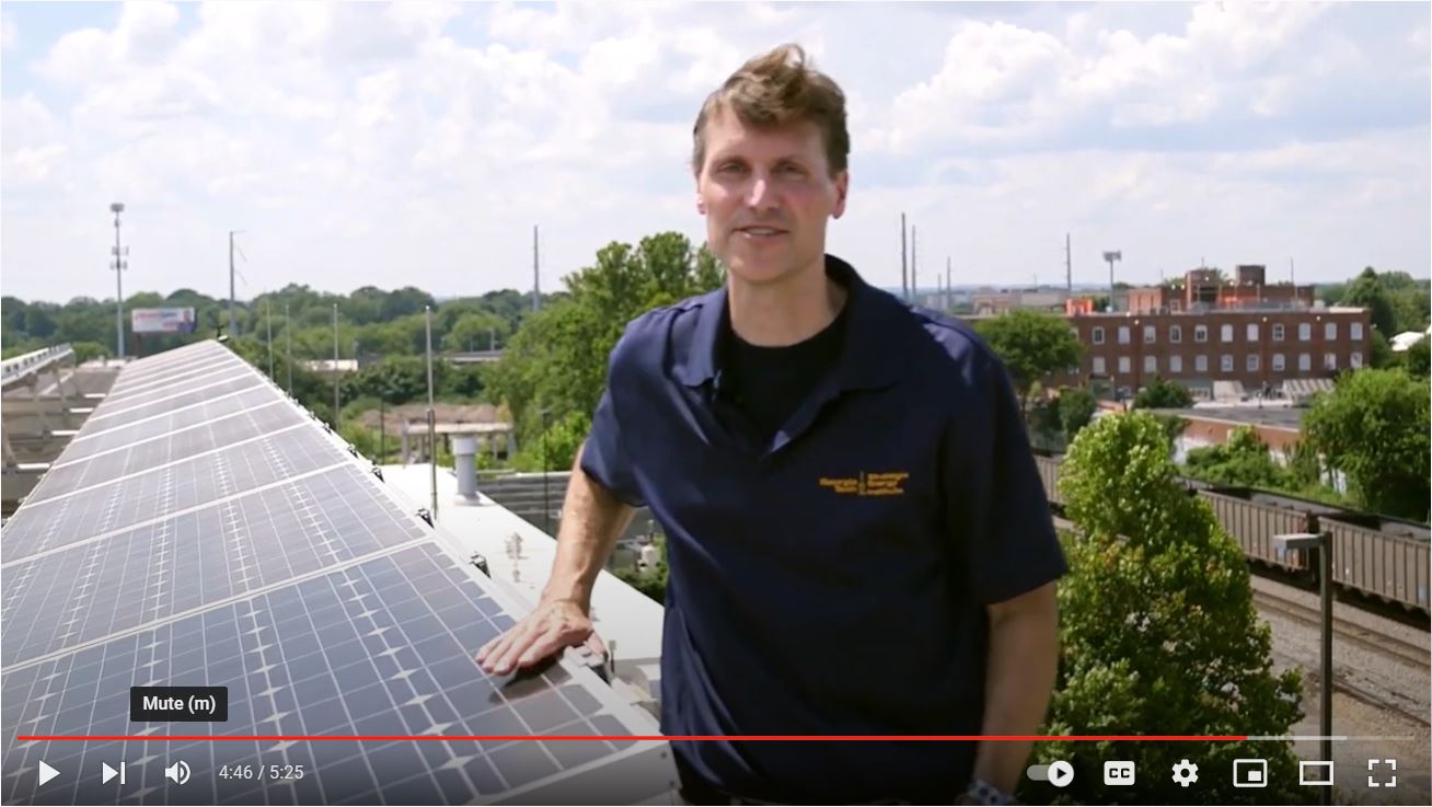 Rich Simmons standing next to a solar array on the roof of the CNES building.