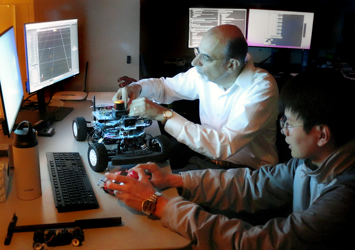 Faculty working with graduate student on a small robotic rover