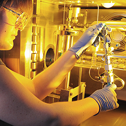 Woman inspects equipment in a chemistry lab.