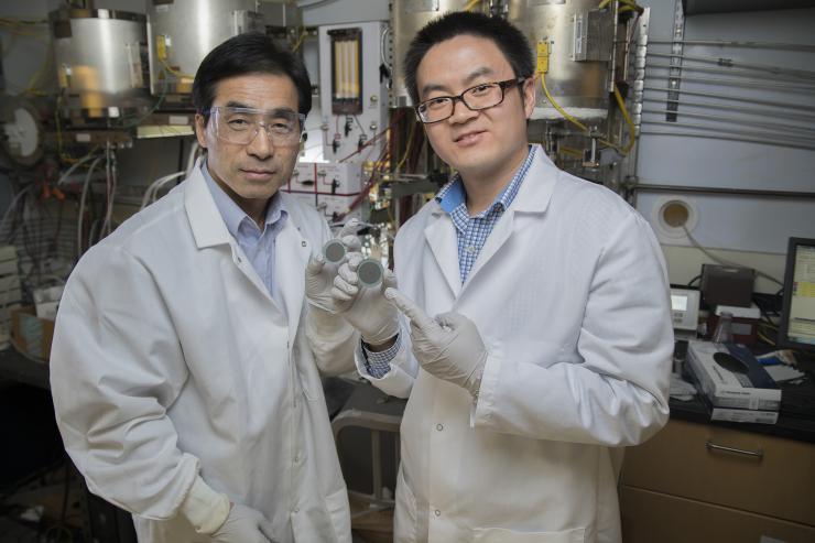 A new catalyst to turbocharge the processing of oxygen in fuel cells: Regents' Professor Meilin Liu (left) with postdoctoral research associate Yu Chen in Liu's lab as they display a disc coated with the catalyst, which works in two phases. The new material also preserves cathodes in solid oxide fuel cells. Credit: Georgia Tech / Christopher Moore