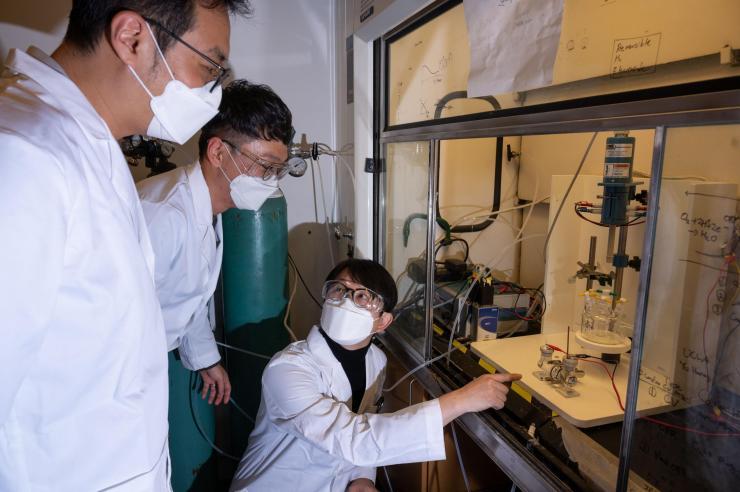 Georgia Tech researchers observe hydrogen and oxygen gases generated from a water-splitting reactor. (Photo credit: Georgia Tech)