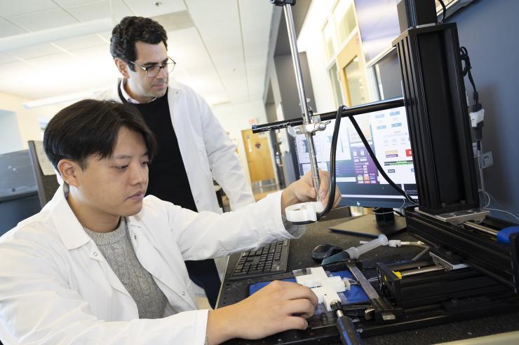<p>Associate Professor Costas Arvanitis and mechanical engineering Ph.D. student Hohyun "Henry" Lee with their closed-loop controlled focused ultrasound system. The uses ultrasound-induced microbubbles to help a powerful immunotherapy target brain tumors and a custom algorithm to continuously fine tune the bubbles for maximum impact.</p>